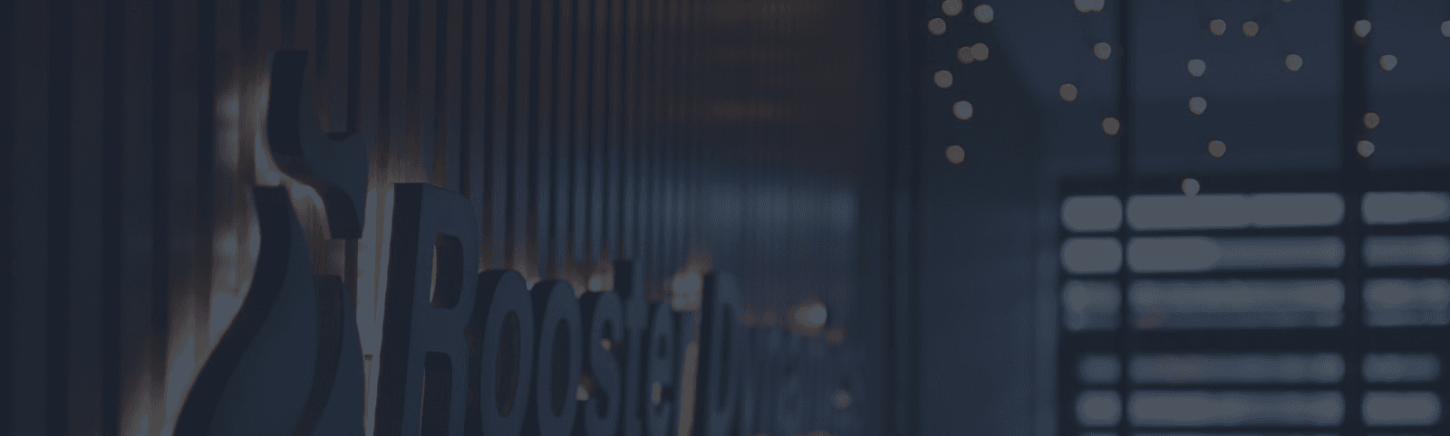 hero image showing part of the rooster dynamics logo beautifully designed from wood, painted in black, with gold backlight, on a slick wooden acustic wall